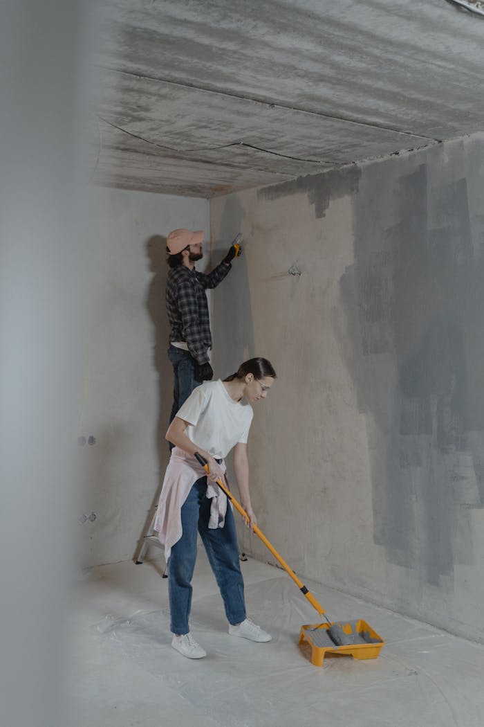 A couple engaged in painting interior walls as part of a home renovation project.